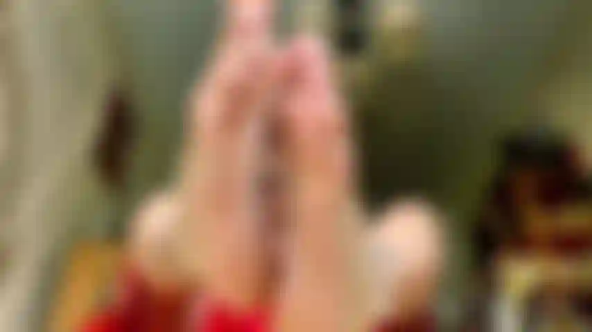 Vestido vermelho esvoaçante com unhas brancas lascadas.