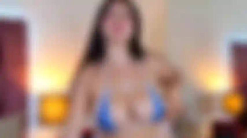 Slowly uncovering her breasts, she provocatively plays with her tongue in a wet and flirtatious way. With a tempting gaze, she stretches out her legs to reveal them full, smooth, and well-cared for.