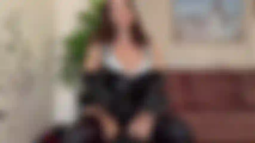 Curvada em látex, de topless, com instruções de masturbação.