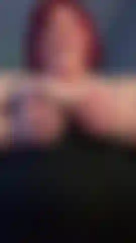 Com cabelo ruivo e uma regata de massagem nos seios.