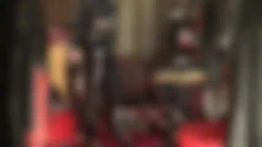 Fetichista de pvc - totalmente vestida em vinil preto brilhante, a amante provoca o fetichista de pvc com jeans brilhantes, saltos altos e um casaco longo.