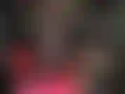 Com pernas cruzadas e estendidas, usando meia-calça preta transparente e sapatos fetichistas.