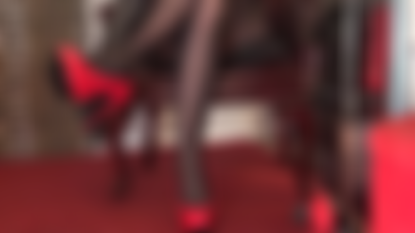 Saltos altos vermelhos brilhantes, luvas de couro pretas e pernas de meia-calça pretas são pura sedução.