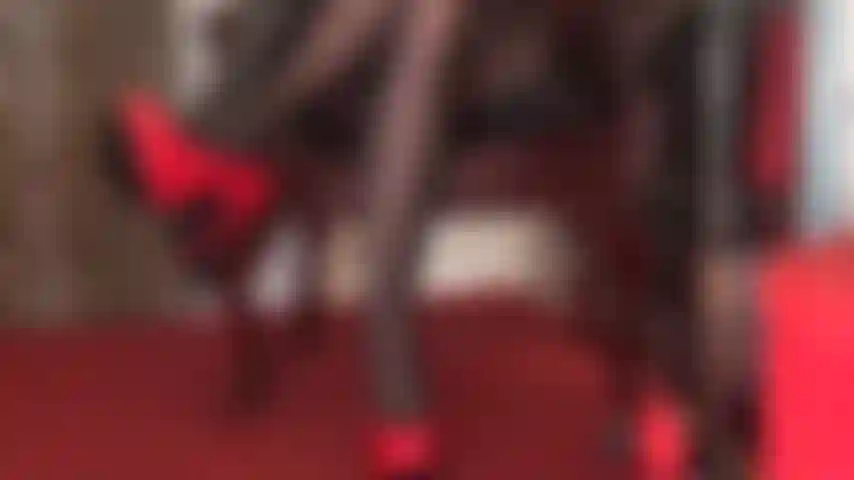 Saltos altos vermelhos brilhantes, luvas de couro pretas e pernas de meia-calça pretas são pura sedução.