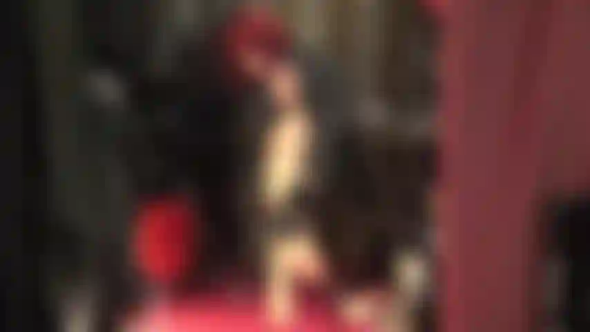 Uma deusa em couro que te provoca com suas pernas quentes em meia-calça bege brilhante e sandálias vermelhas de tiras no tornozelo.