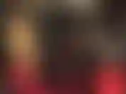 Uma amante loira com um macacão apertado de pvc brilhante.