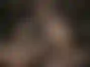 Uma deusa do couro usando óculos sensuais, acariciando seu enorme strapon branco.