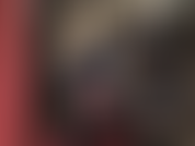 Uma senhora vestida com um macacão de vinil preto brilhante, com um de seus enormes paus amarrados com uma cinta branca e grossa, empurrando e batendo.