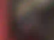 Uma senhora vestida com um macacão de vinil preto brilhante, com um de seus enormes paus amarrados com uma cinta branca e grossa, empurrando e batendo.