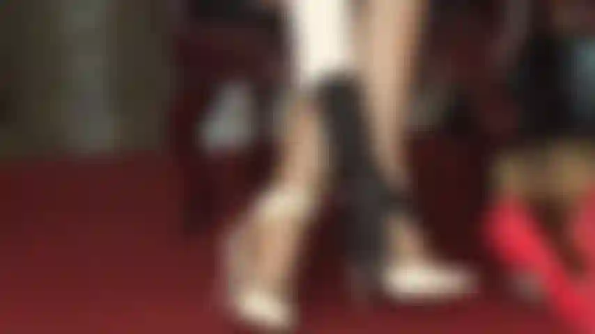 Sandálias brancas de tiras e meia-calça brilhante provocam os pés.