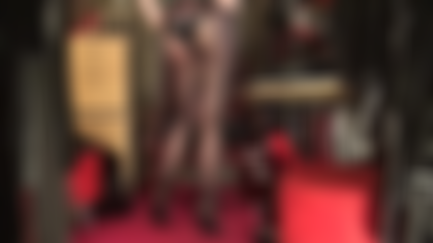 Com pernas de tirar o fôlego, vestida com meia-calça preta de seda transparente, pés em um par sexy de mules de couro de salto alto e um body de látex brilhante para completar o visual irresistível.