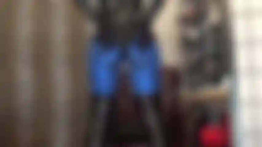 Com leggings de lycra azul metálica e body de pvc brilhante, pés em meia-calça marrom escuro.