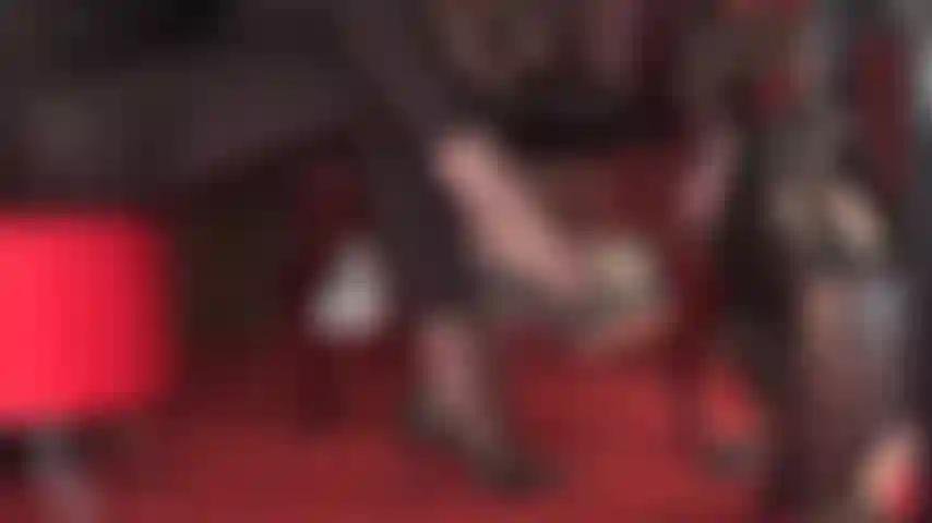 Delicie-se com esta vista lateral de sapatos de couro pretos pendurados em meias-calças e leggings de spandex brilhantes.