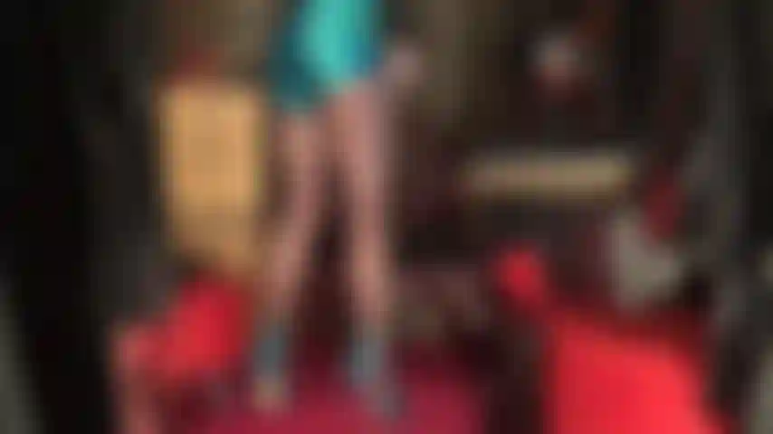 Admiro as pernas longas e fortes da minha amante, vestidas com meias-calças transparentes marrom-café que levam até um short de cetim azul extremamente brilhante.