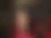 Uso meia-calça nude sexy, cabelo preto, couro preto, body vermelho e sapatos de salto alto com tiras vermelhas no tornozelo.