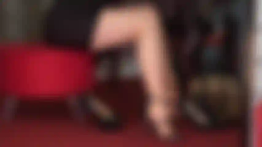 Que seduz pernas e pés com meia-calça bronzeada e vários pares de saltos altos pretos e sensuais.