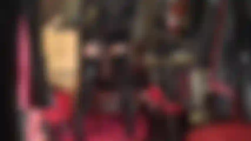 Usando um body de pvc e nylon - botas de cano alto, meia-calça brilhante, saia de pvc e um body de nylon transparente por baixo.