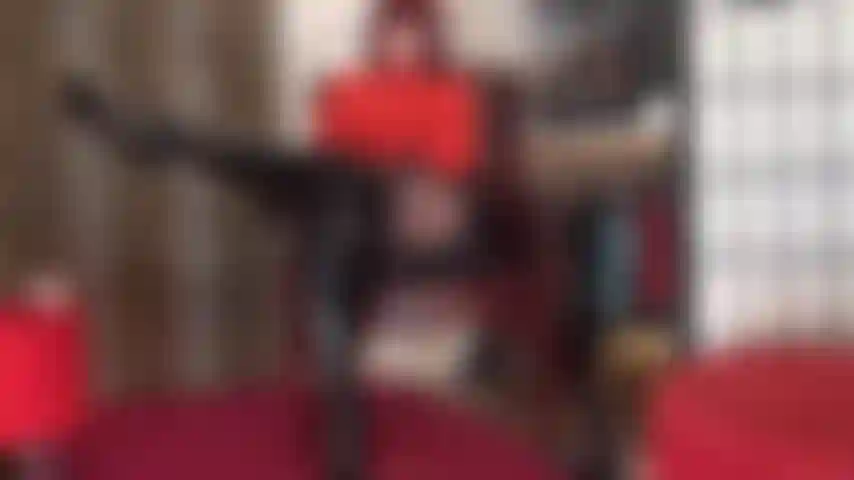 Que adora o corpo com esta roupa sexy de body vermelho, saia de vinil brilhante, meia-calça preta e botas de couro envernizado pretas até os joelhos.