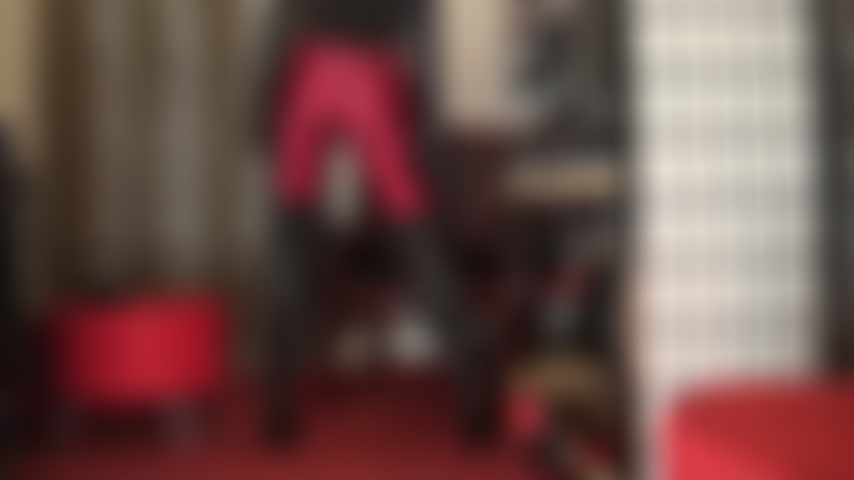 Com roupa fetichista em vermelho e preto - adoração de bunda com meia-calça de spandex vermelho escuro brilhante com botas de couro acima do joelho, luvas longas de couro e, eventualmente, combinadas com shorts sensuais de lycra de cintura alta.