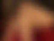 Com pernas cruzadas de nylon nude e sapatos vermelhos brilhantes.