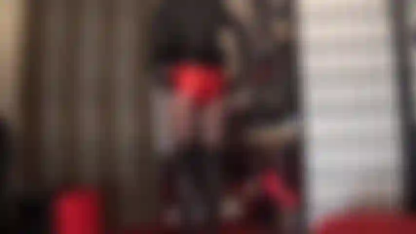 Que faz tortura e ordenha de pica usando shorts vermelhos metálicos e couro preto.