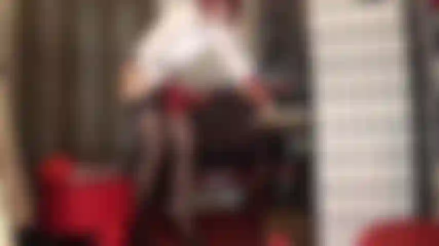 Coberta de meias vermelhas, assando e assando no espeto com uma cinta-liga preta e grossa. Paus grandes te pegam de ambos os lados.