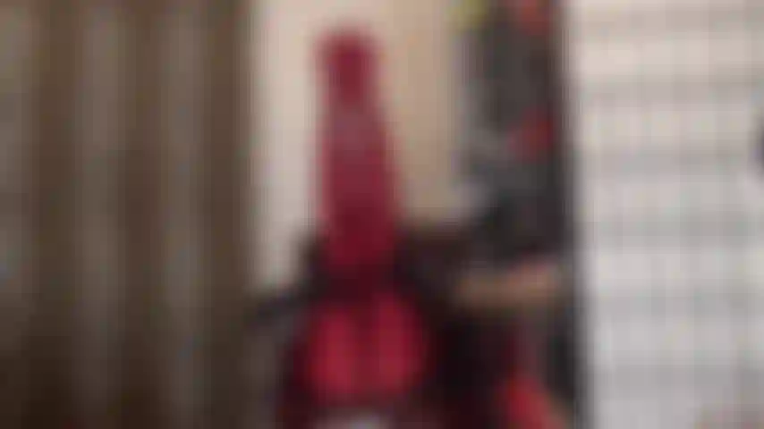 Com as pernas para cima, usando meia-calça de lycra vermelha brilhante e fazendo footjob em um vibrador sem cortes.