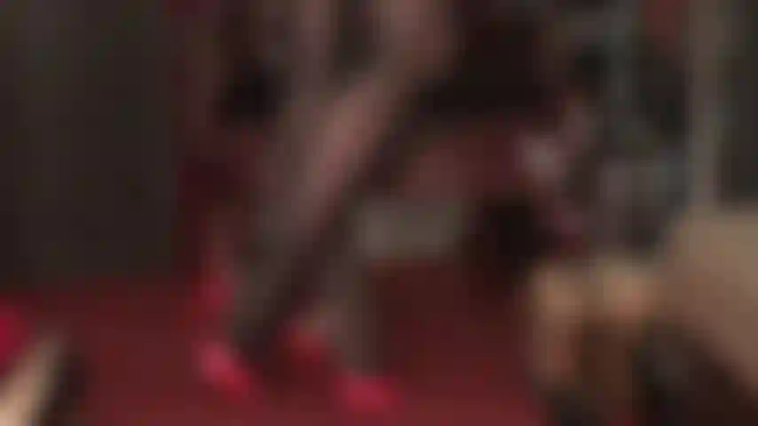 Uso meia-calça preta extra brilhante com brilho de óleo e mules vermelhos de salto alto.