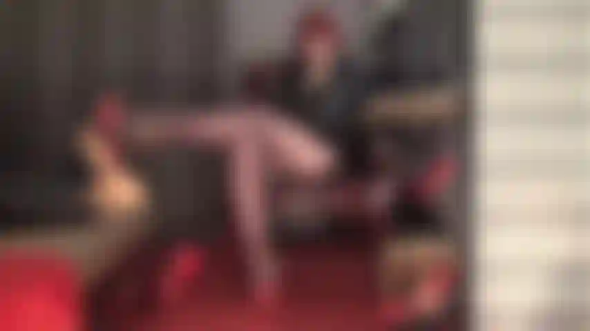 Amarrada e pulsando aos pés da senhora - suas pernas e pés são sua paixão, seu toque suave, seu desejo. A senhora faz sua cabeça girar em mules vermelhos de salto alto e meia-calça marrom café.