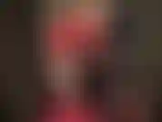 Senhora vivian, vestida em látex vermelho brilhante, pernas nuas, saltos altos e luvas longas e brilhantes.