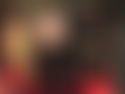 Uma visão sob a saia larga e sexy de vinil da amante revela meia-calça preta transparente e botas altas e brilhantes.