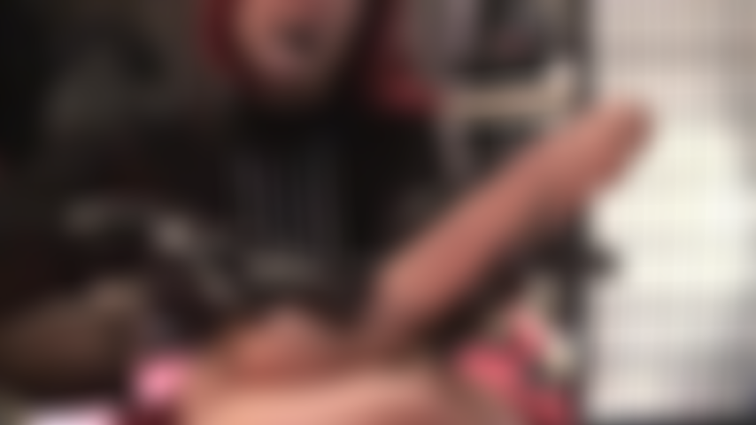 Uma senhora com um olhar severo e batom preto, que ordenha seu pau e provoca seu cu com luvas de látex pretas.