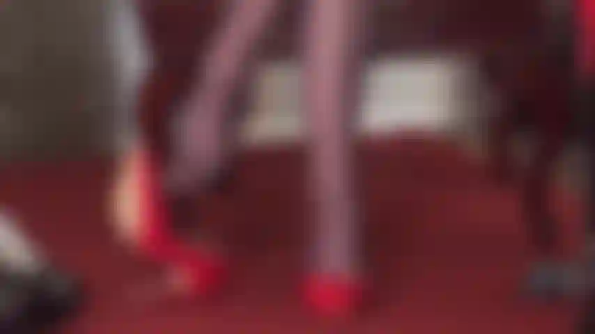 A senhora vivian exibe suas habilidades de balanço com um par de sapatos vermelhos brilhantes e meia-calça marrom escura brilhante, com um chicote de montaria na mão.