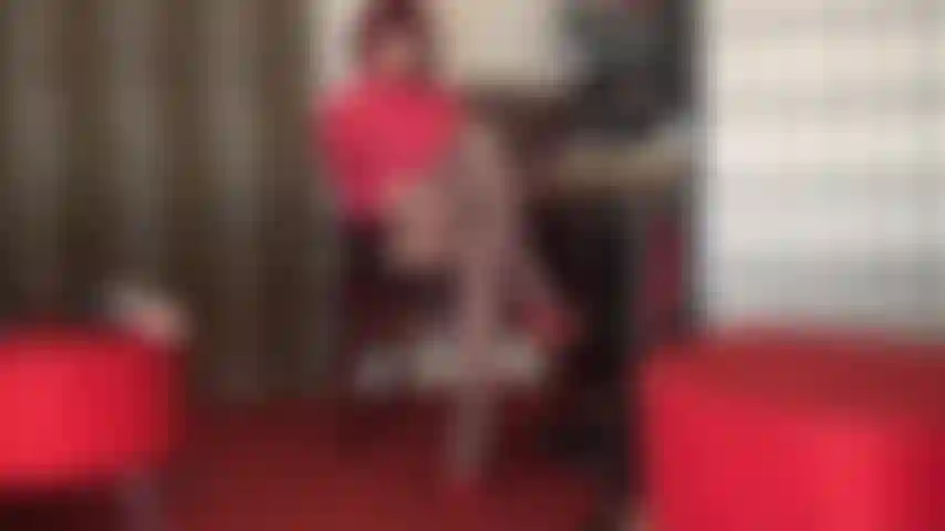 A senhora tem o seu pau de escravo coberto de meia preso no espaço entre as coxas cruzadas dela.