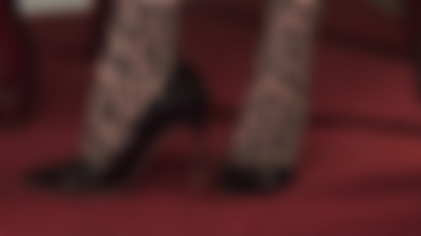 A perfeição do salto alto brilhante - vestindo uma meia-calça com estampa de leopardo, a amante modela seus brilhantes sapatos de verniz preto.