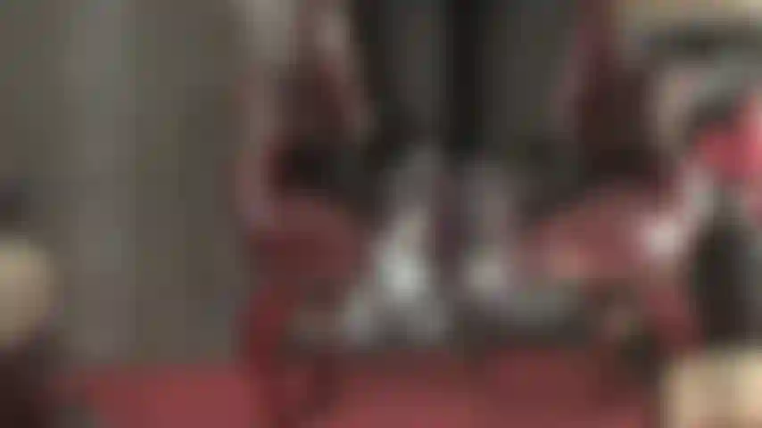 A senhora tira os saltos, com os pés de meia-calça transparentes balançando para fora da cadeira.