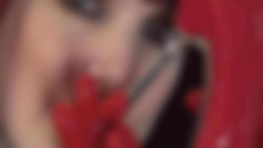 Com luvas fetichistas de látex vermelho, saltos de aço vermelho, sapatos de verniz e um pau preto provocante.