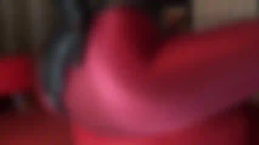 A mistress exibe suas curvas magníficas neste traje fetiche quente de meia-calça de lycra vermelho bordô, body de pvc, botas de salto alto e luvas de couro.
