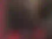 Uma deusa fetichista de látex excêntrica, vestida com um macacão de borracha preto com capuz e uma cinta-liga preta.