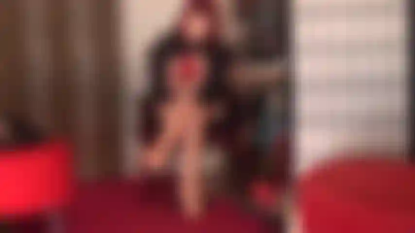 Tentadora de vermelho - a amante vivian veste um par de meias de renda vermelha sobre uma meia-calça nude brilhante, sapatos de salto alto vermelhos e luvas de couro vermelho.