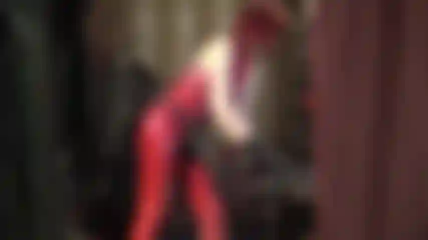 Com uma cinta-liga preta enorme e um macacão de borracha vermelho.