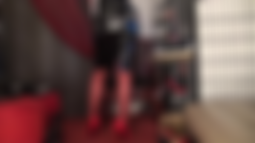 Meia-calça vermelha, salto alto e saia de vinil preta brilhante.