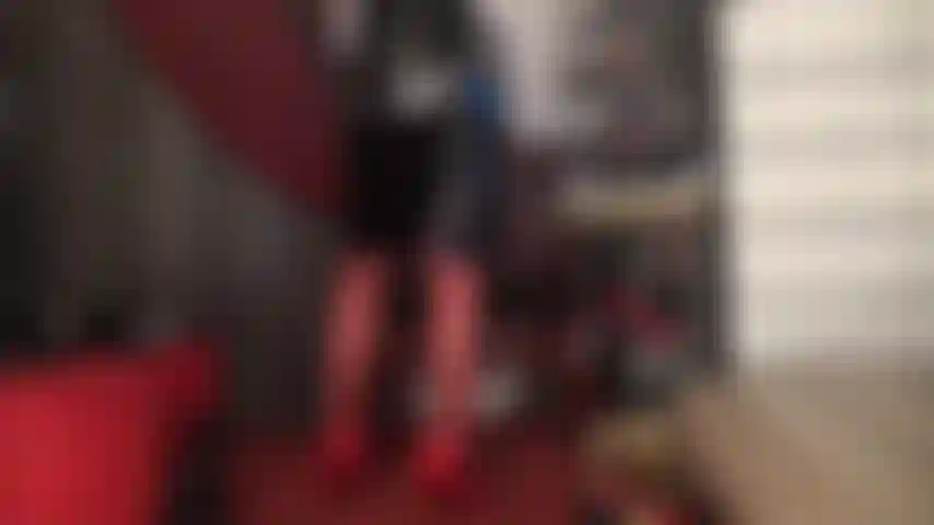 Meia-calça vermelha, salto alto e saia de vinil preta brilhante.