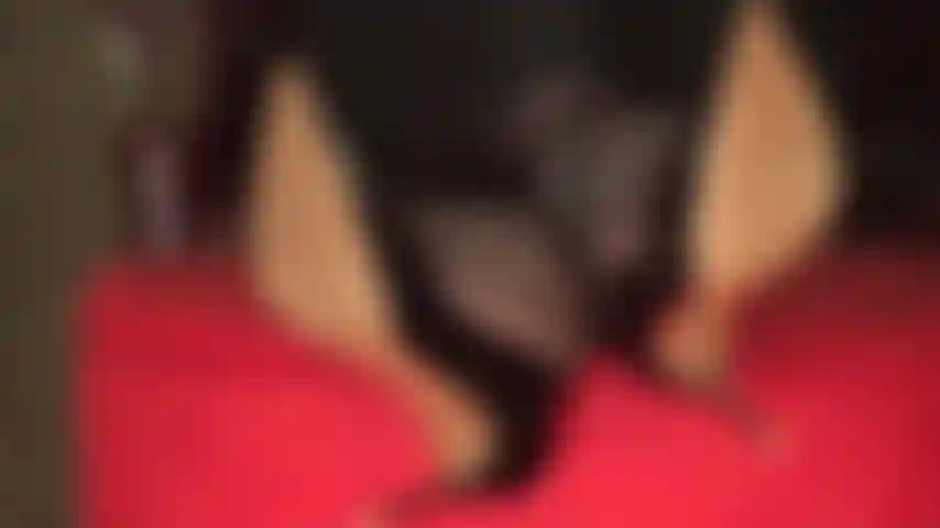 Que brinca de balançar e de sapato com os tornozelos cruzados e os pés em cima do pufe.