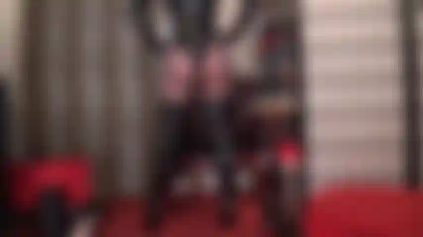 Curvas brilhantes de perfeição - uma sedutora brilhante exibe suas curvas de perfeição em um body de pvc, botas altas acima do joelho e meia-calça preta transparente.