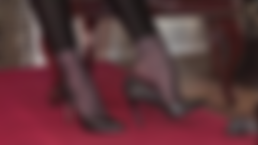 Com arcos altos e sensuais, usando meia-calça preta, leggings e sapatos de couro de salto alto.