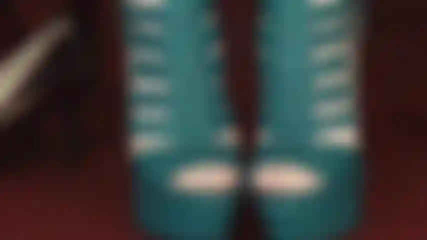 Com meia-calça branca transparente e botas peep toe de cadarço azul-petróleo.