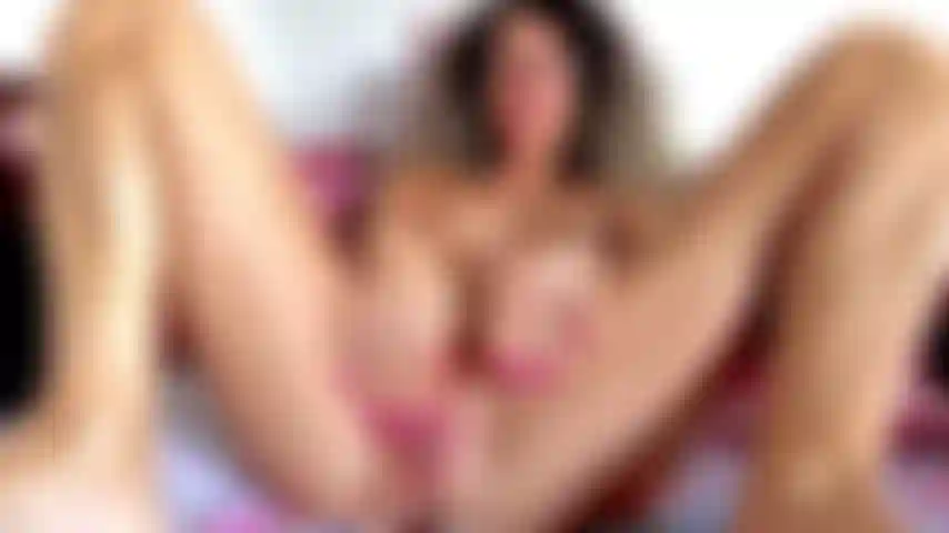 Abro os lábios grandes da minha bucetinha, provocando meu clitóris duro, deitada, toda nua, pernas bem abertas, exibindo minha bucetinha molhada, mamilos grandes.