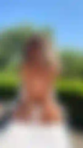 Tomando banho de sol em topless, de frente para você de joelhos.