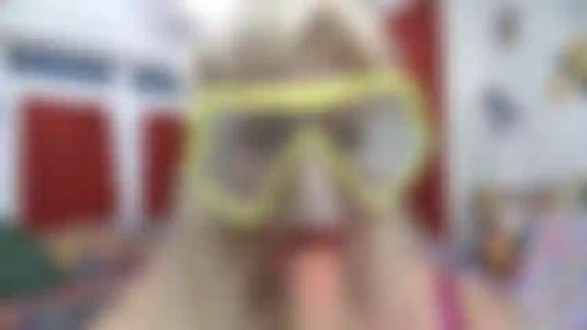 Pov do rosto com máscara de mergulho embaçando-o com batom vermelho chupando um brinquedo branco.